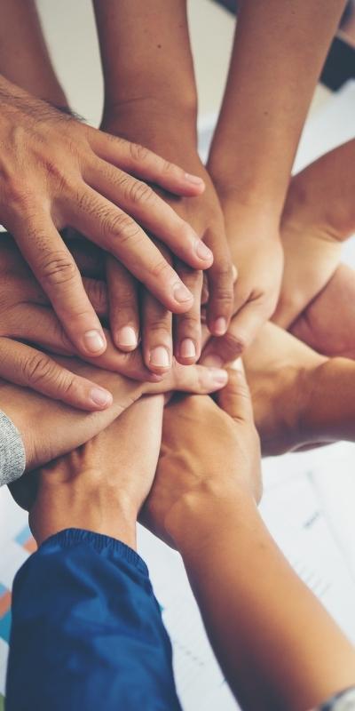 Image of people in circle putting hands in for teamwork